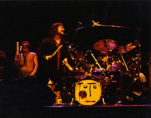 The band Toto playing live music; their percussionist plays a jestick
